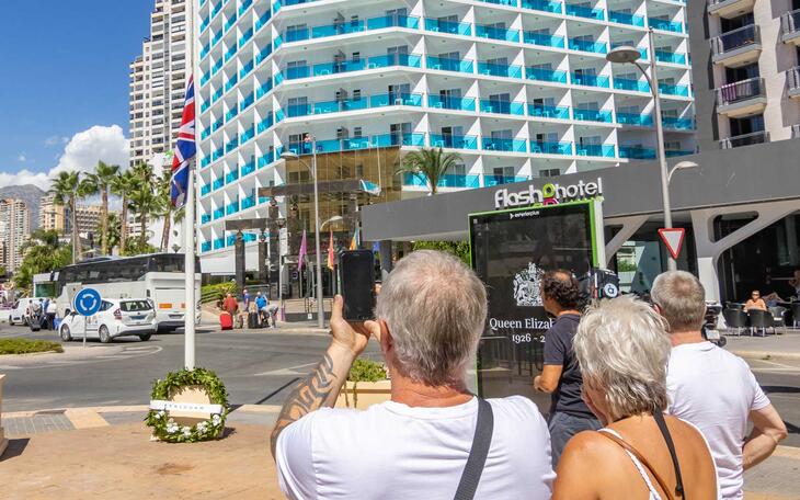 Turistas británicos ante la bandera a media asta en la plaza Derramador.